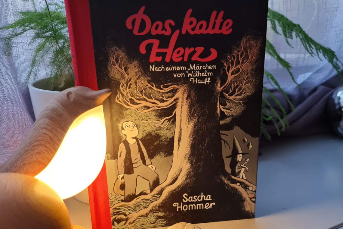 Sascha Hommer Das kalte Herz Titelbild zeigt eine Leuchte in Vogelform und das Buch mit rotem Leinenrücken